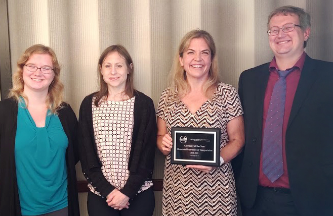 Four people pose with an award plaque