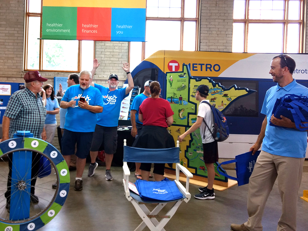 Several volunteers are at work in the OTAT booth at the Minnesota State Fair. The booth features a large map of Minnesota.