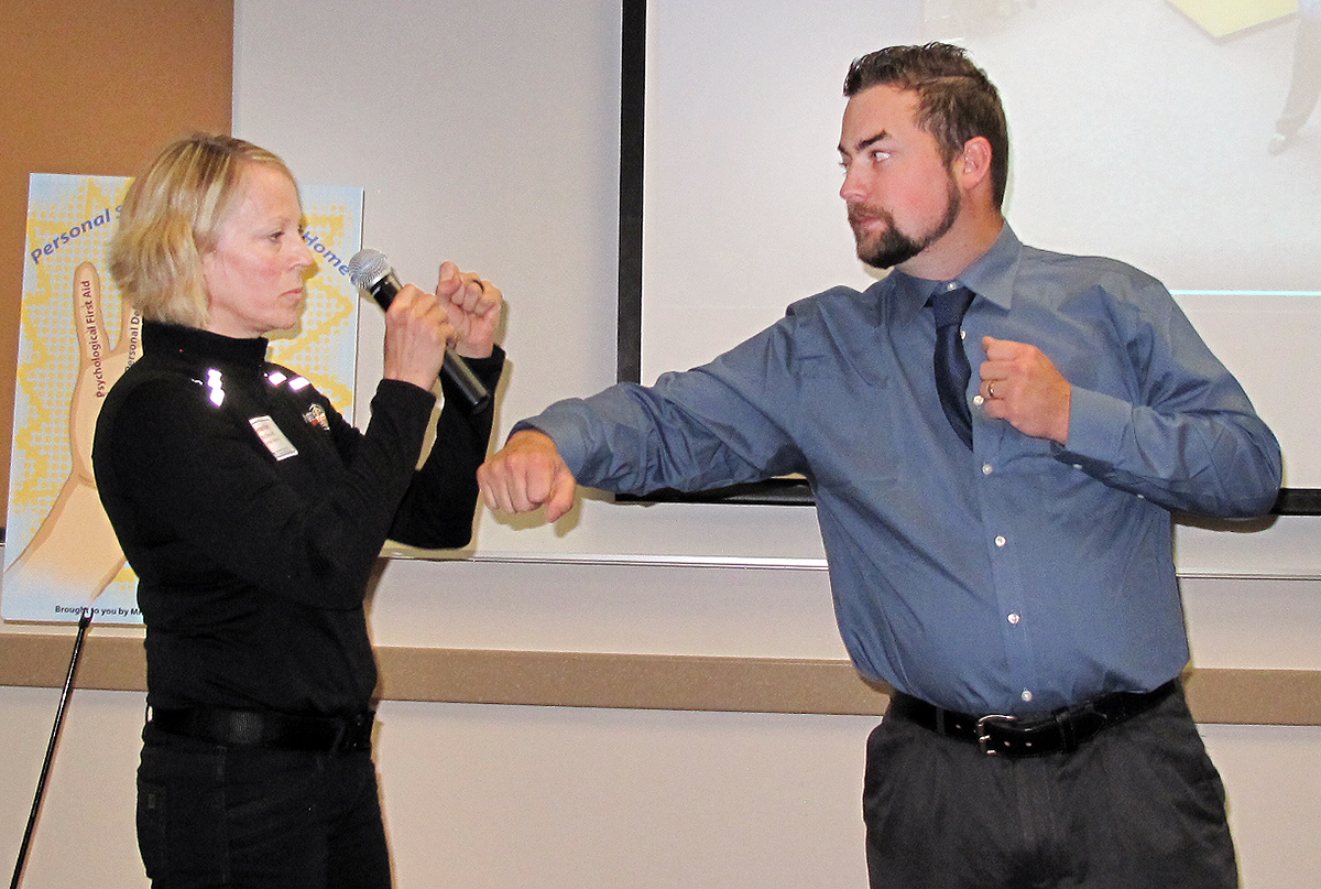 A man pretends to throw a punch at a woman, who pretends to block it as part of a demonstration of self-defense techniques