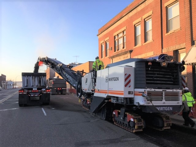 Photo: large machinery at work on a city street next to a building.