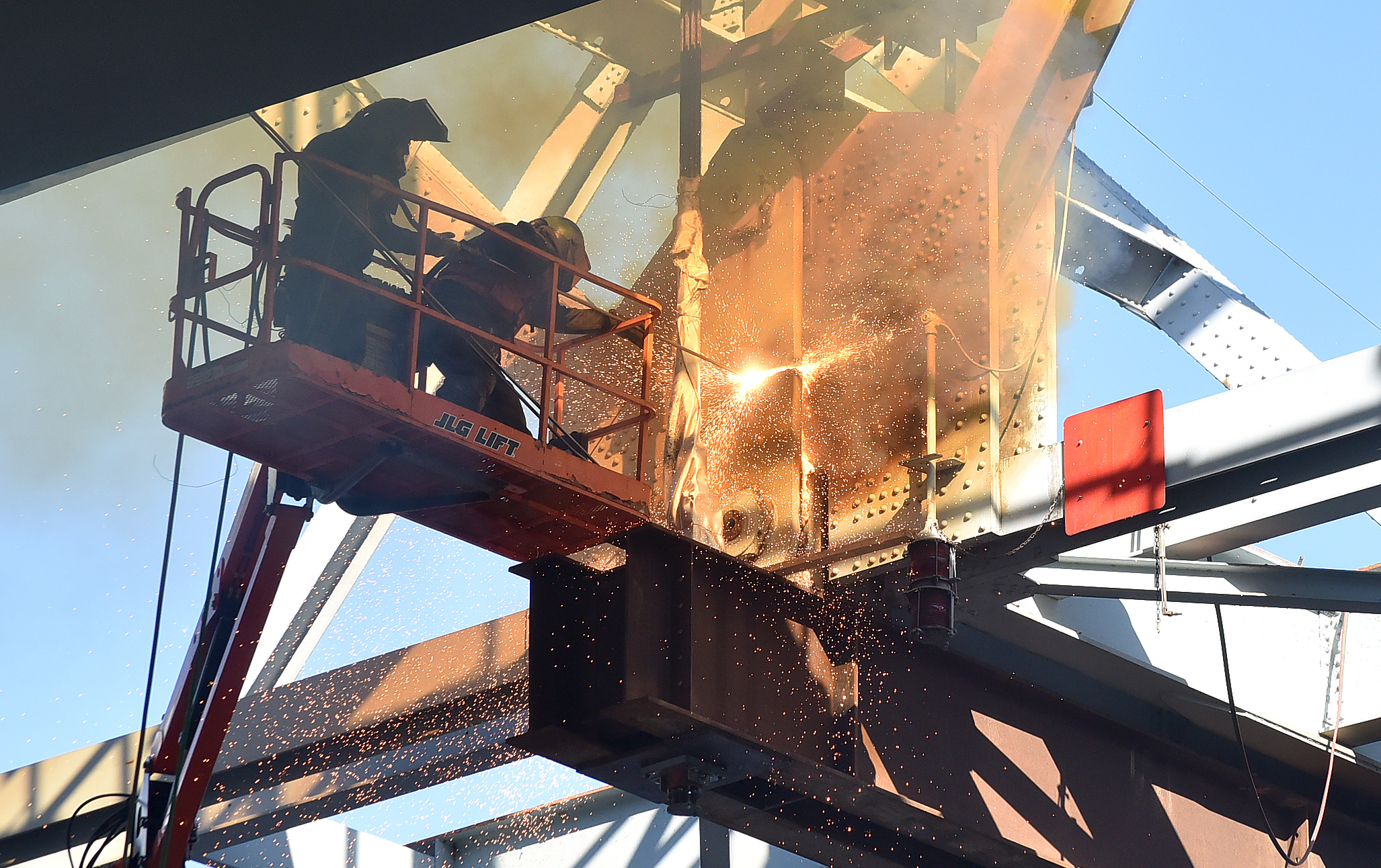 Photo: Workers in protective gear use tools to cut through metal plates on the Red Wing Bridge.