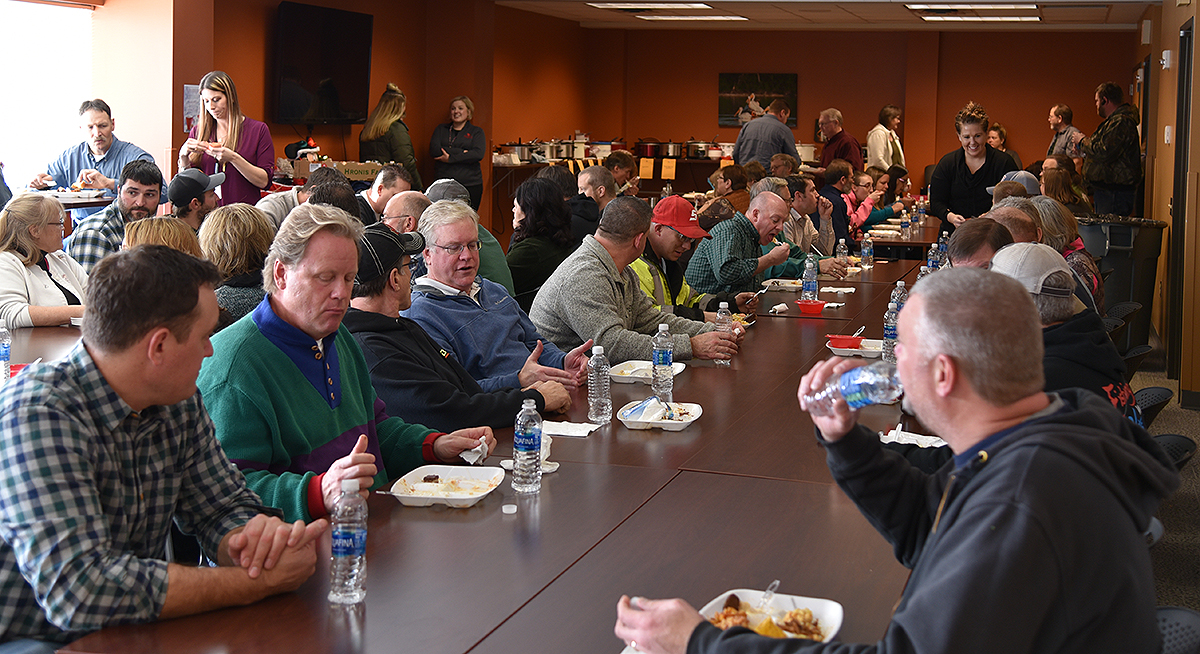 Photo: people seated at long tables during the potluck