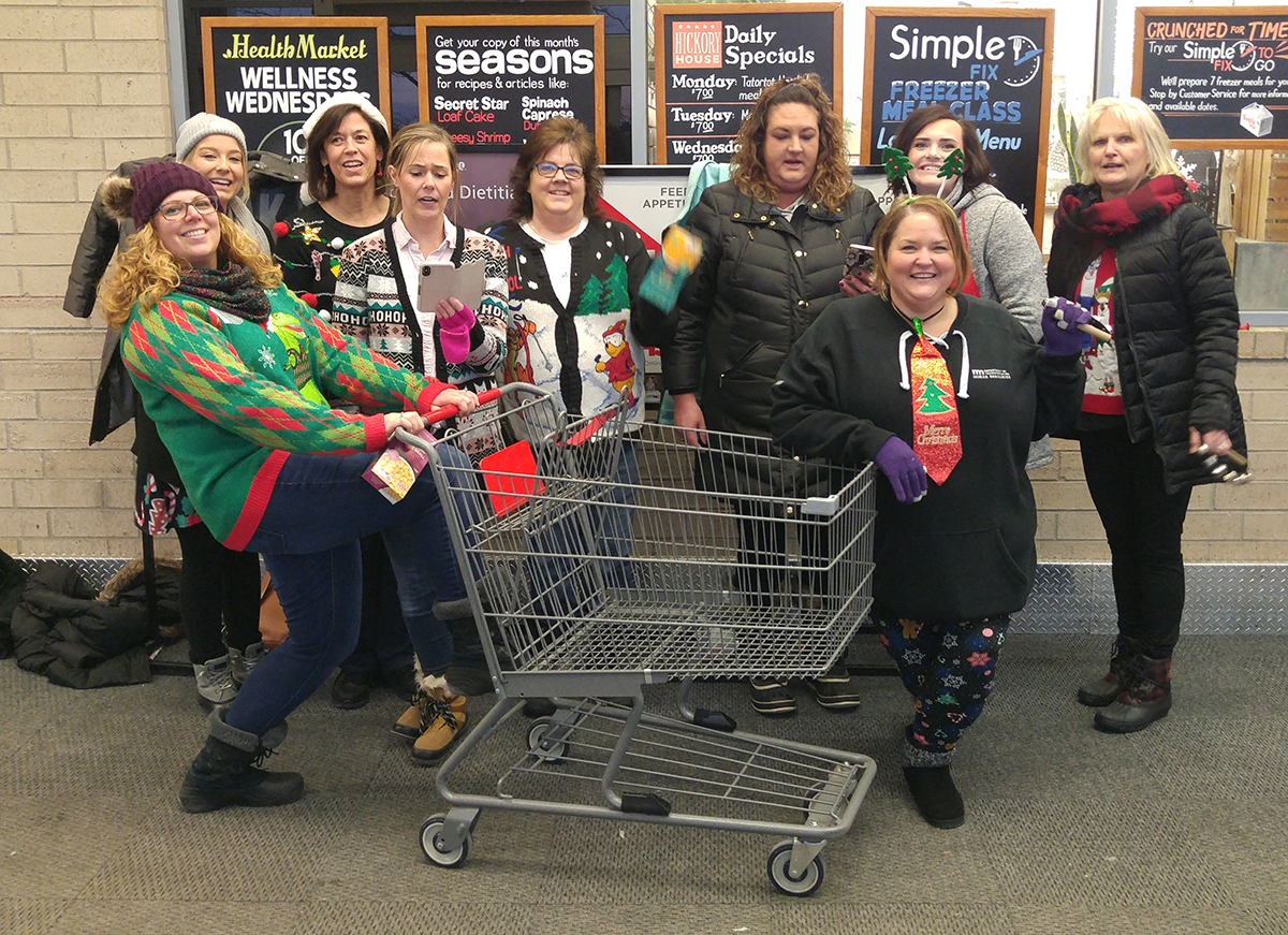 Photo: nine women gathered around a shopping cart