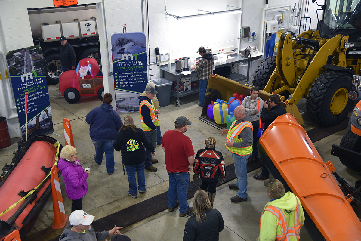 Photo: Overhead shot of people gathtered in the new Evansville truck station. MnDOT employees are wearing yellow safety vests.