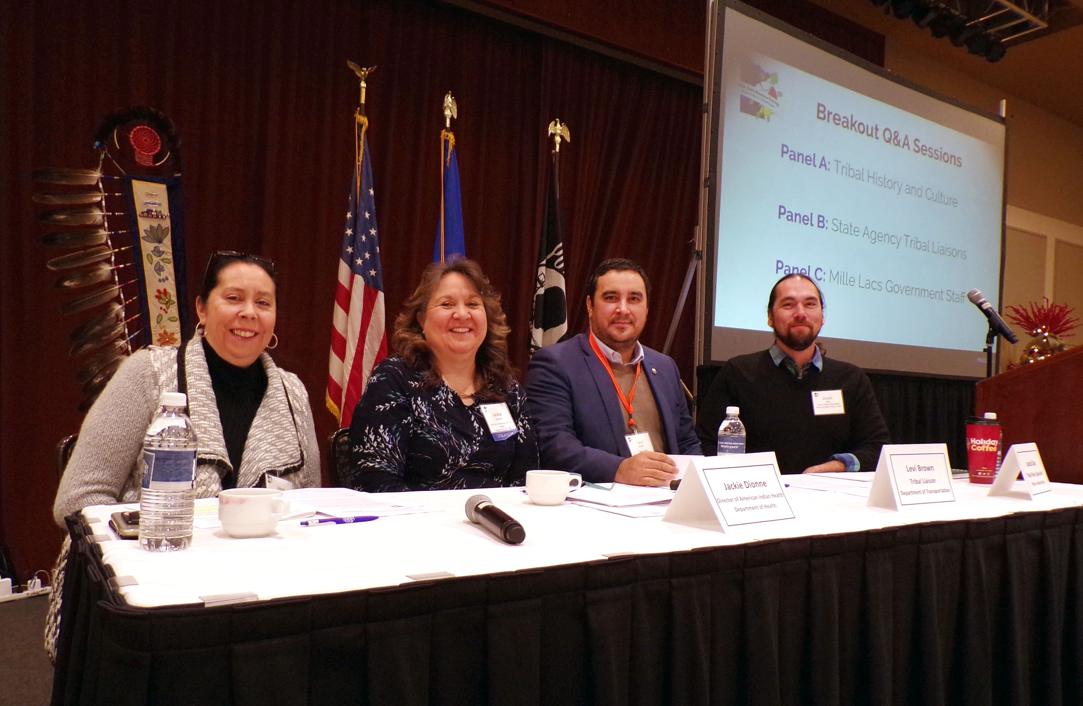 Photo: four people on a stage seated behind a table