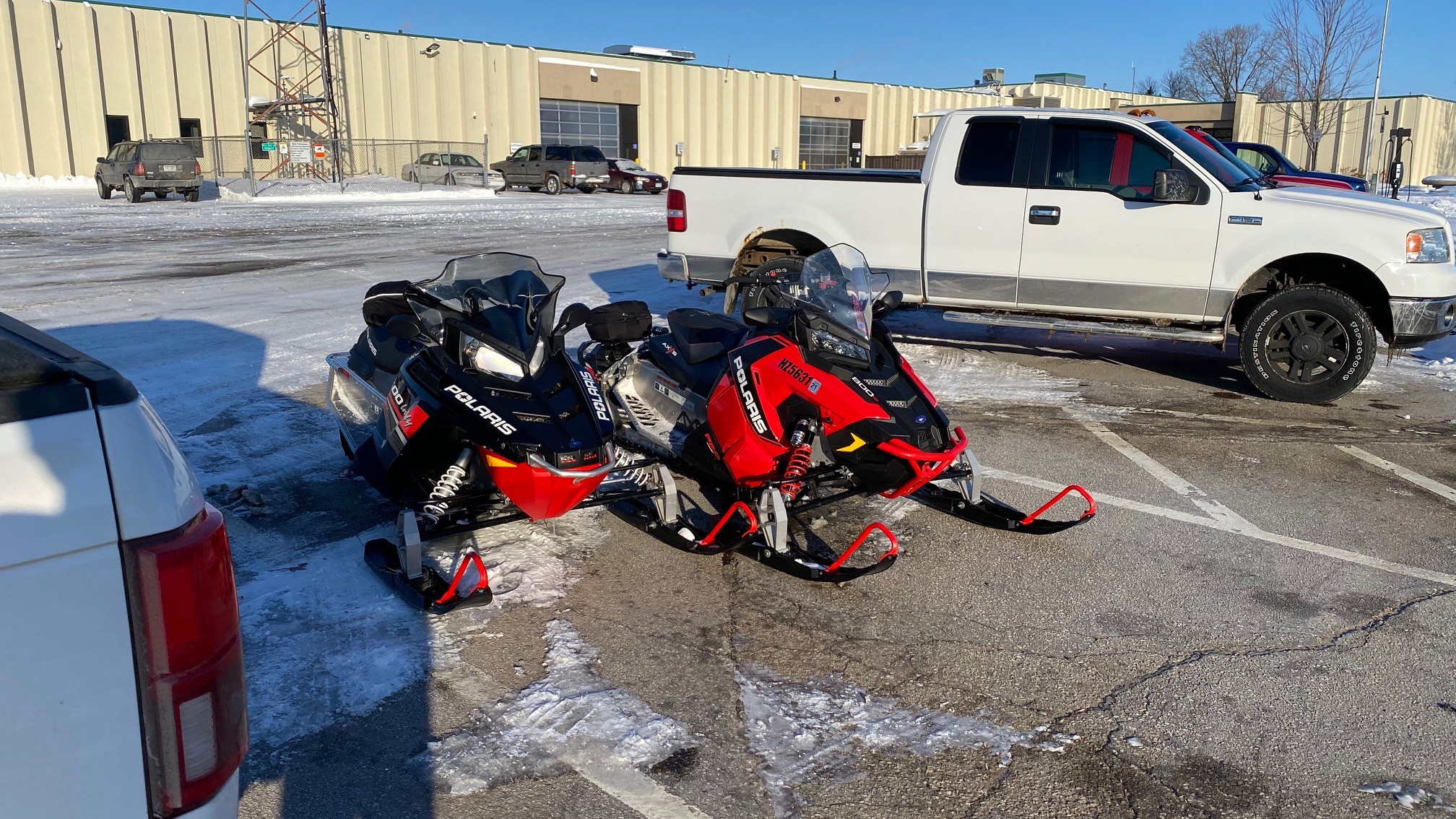 Photo: two snowmobiles parked in a MnDOT employee lot