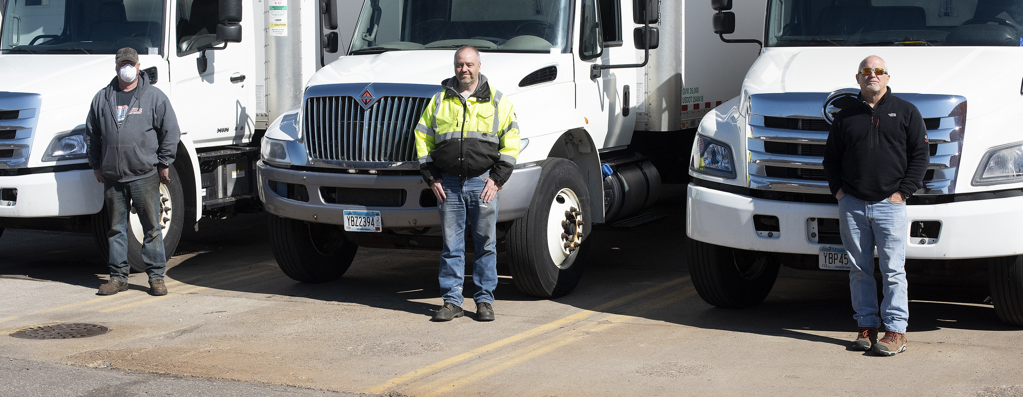 Photo: three men standing in front of trucks