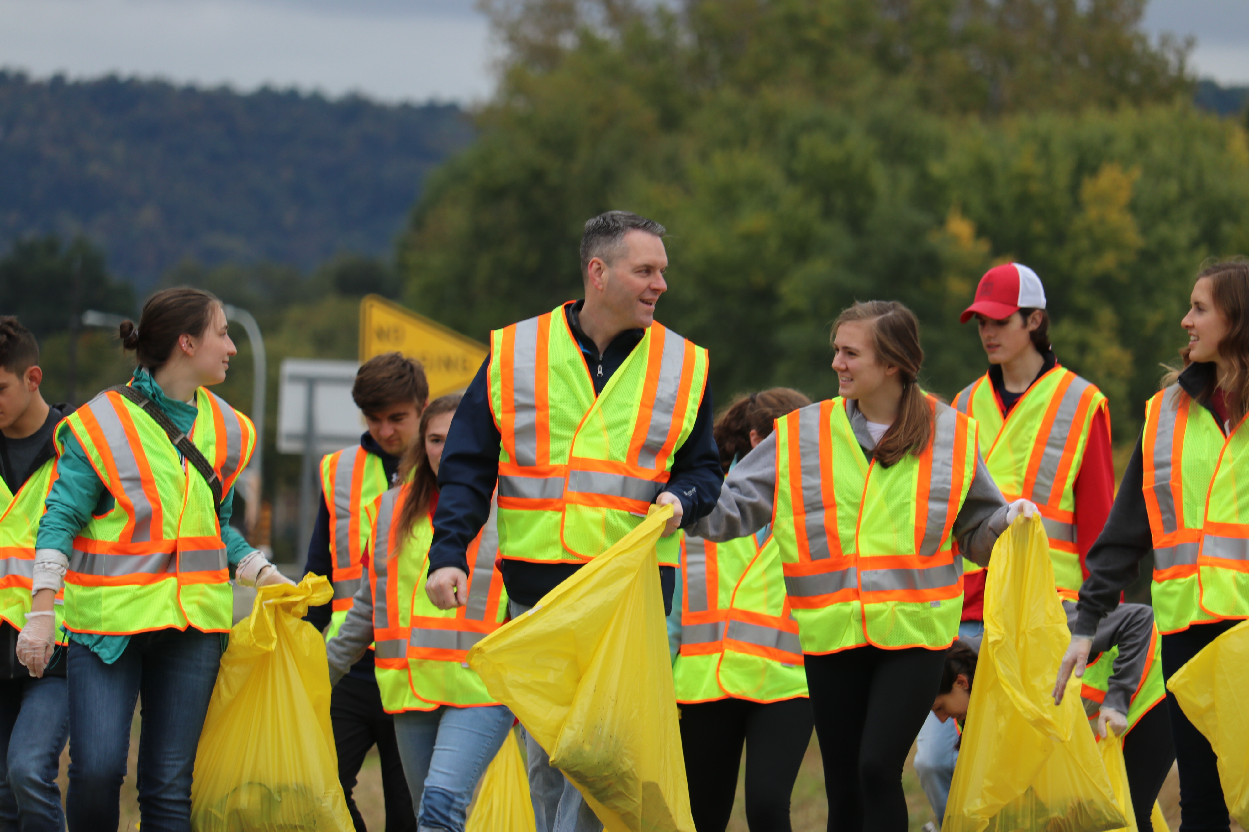 Photo: people in yellow safety vests picking up trash