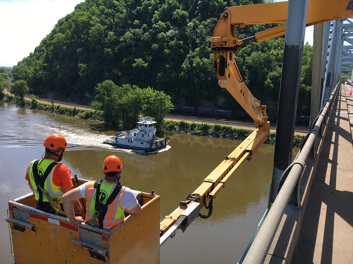 Photo: a work crew on a bridge, looking out over a river