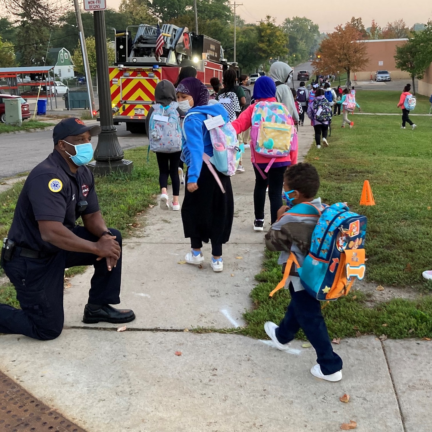 Photo: Children walking past a firefighter on their way to school.