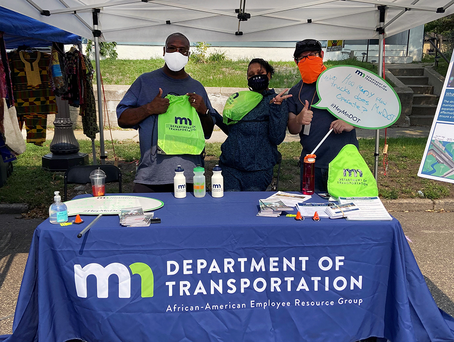 Photo: MnDOT employees behind a table with a MnDOT logo on it