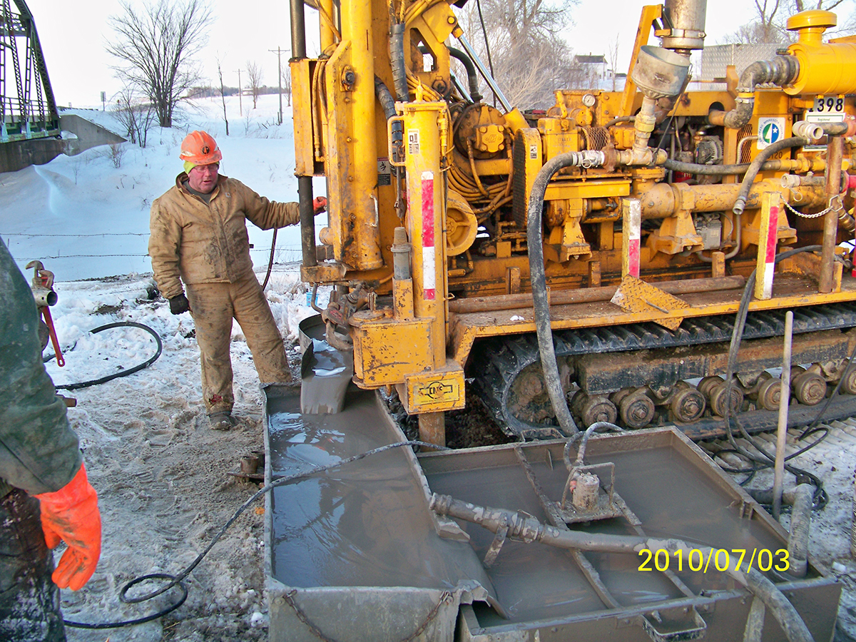 Photo: a worker standing next to a large drilling rig