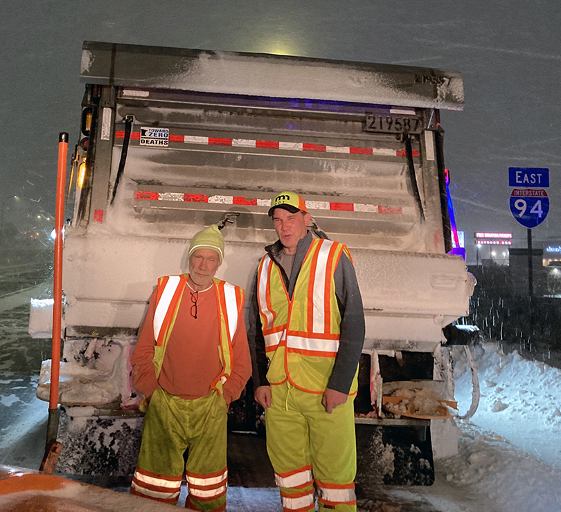 Photo: two people standing by a snowplow