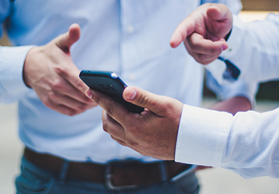 Photo: Hands pointing to cell phone.