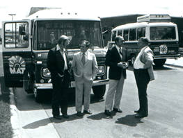 4 legislators in front of buses (b&w)