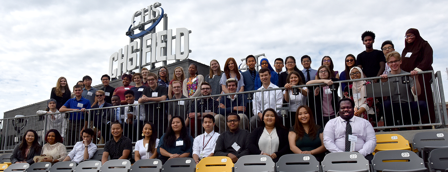 Three rows of workers looking at the camera. Behind them is the CHS field sign.