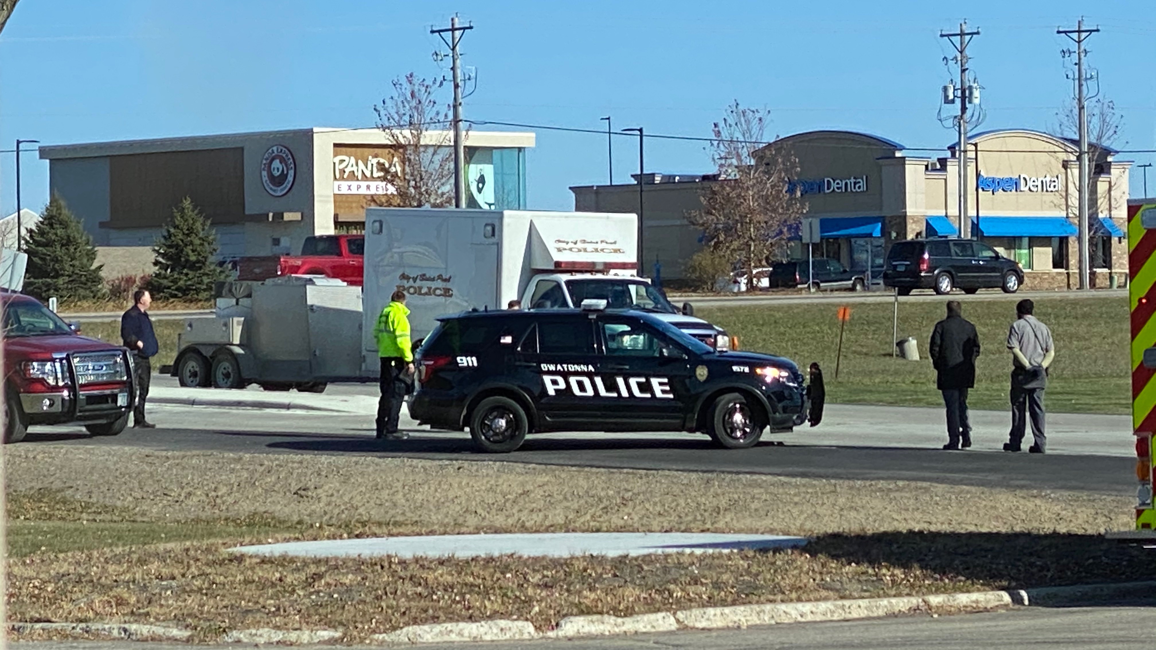 Police vehicles block an intersection near the Owatonna truck statuon, as officers stand by