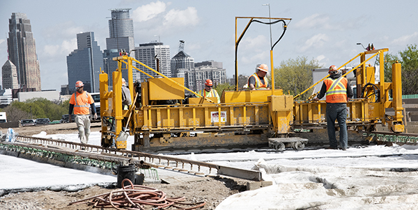 A large yellow machine is being operated by a work crew