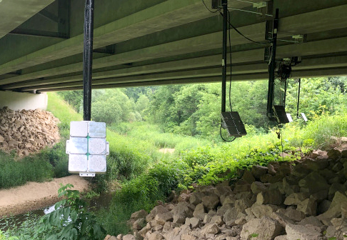 Ultrasonic devices, which resemble music speakers, are mounted on the underside of a bridge