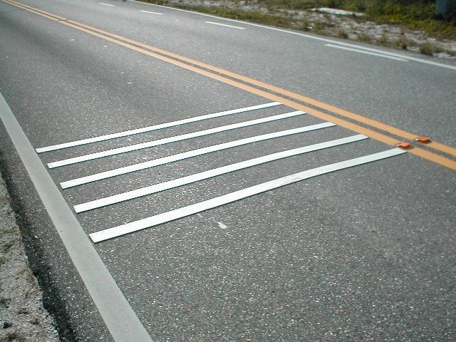 Photo: This transverse rumble strip consists of four raised lines going all the way across a lane on a road.
