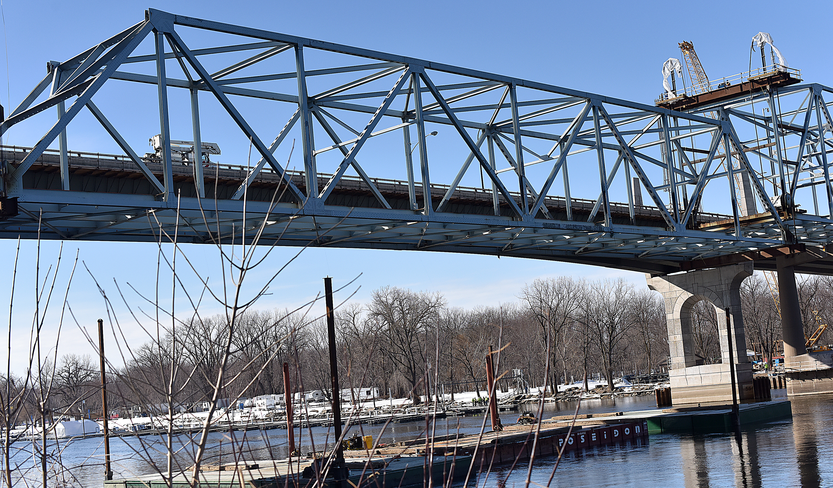 Photo: The steel framework of the bridge's center span is being slowly lowered onto a barge.