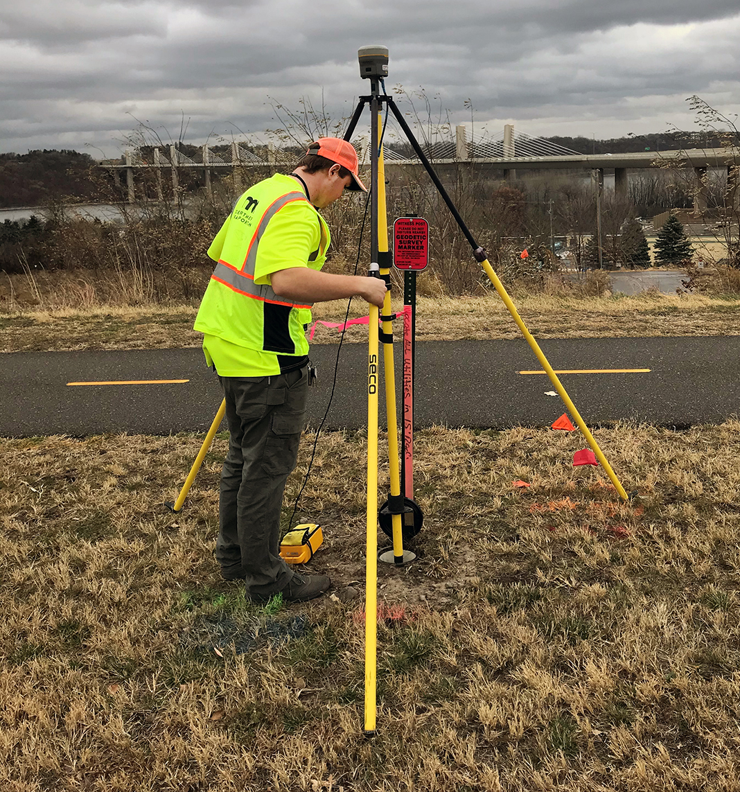 Photo: a surveyor setting up equipment for an observation near a bridge