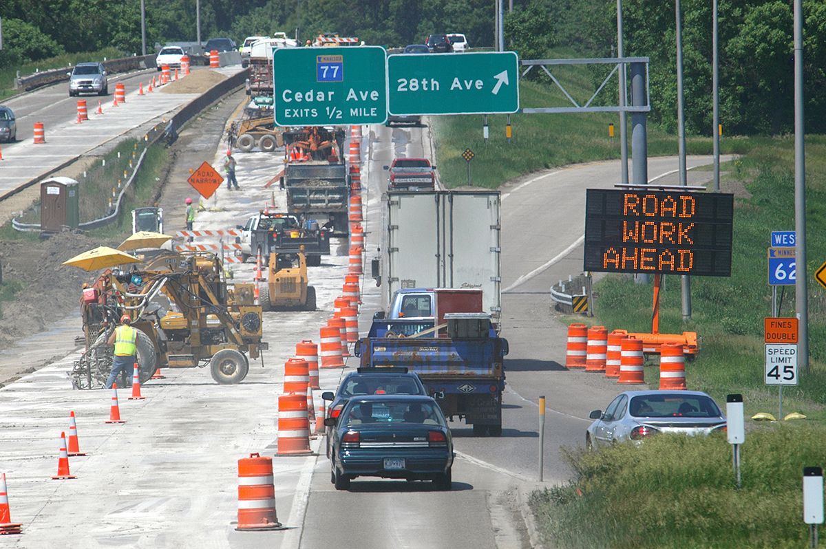 Photo: traffic passing a sign that reads road work ahead