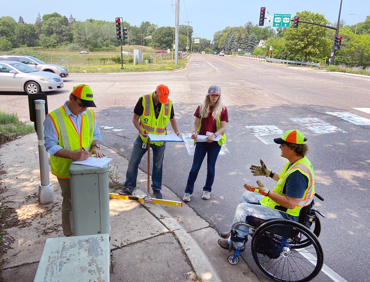 Photo: Three MnDOT staff members and a consultant review and evaluate a crosswalk
